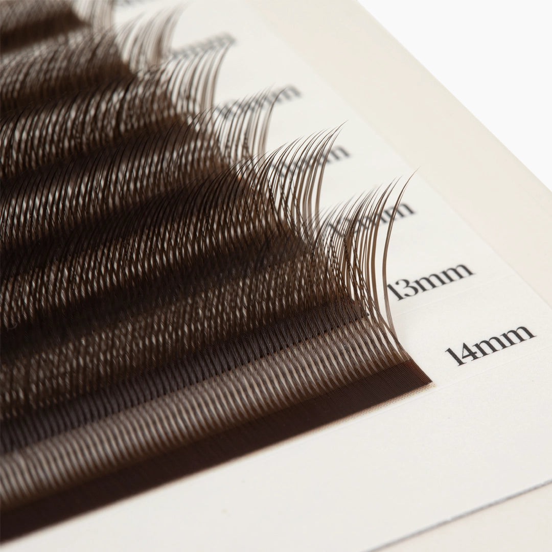 Extreme macro close-up of dark brown Kitten Lash extensions on length-marked strips, highlighting their density and curl.